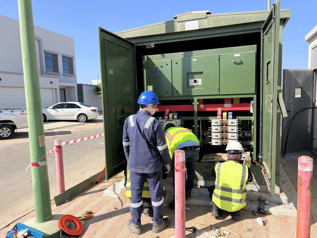 Electricians terminating cables at an open kiosk substation